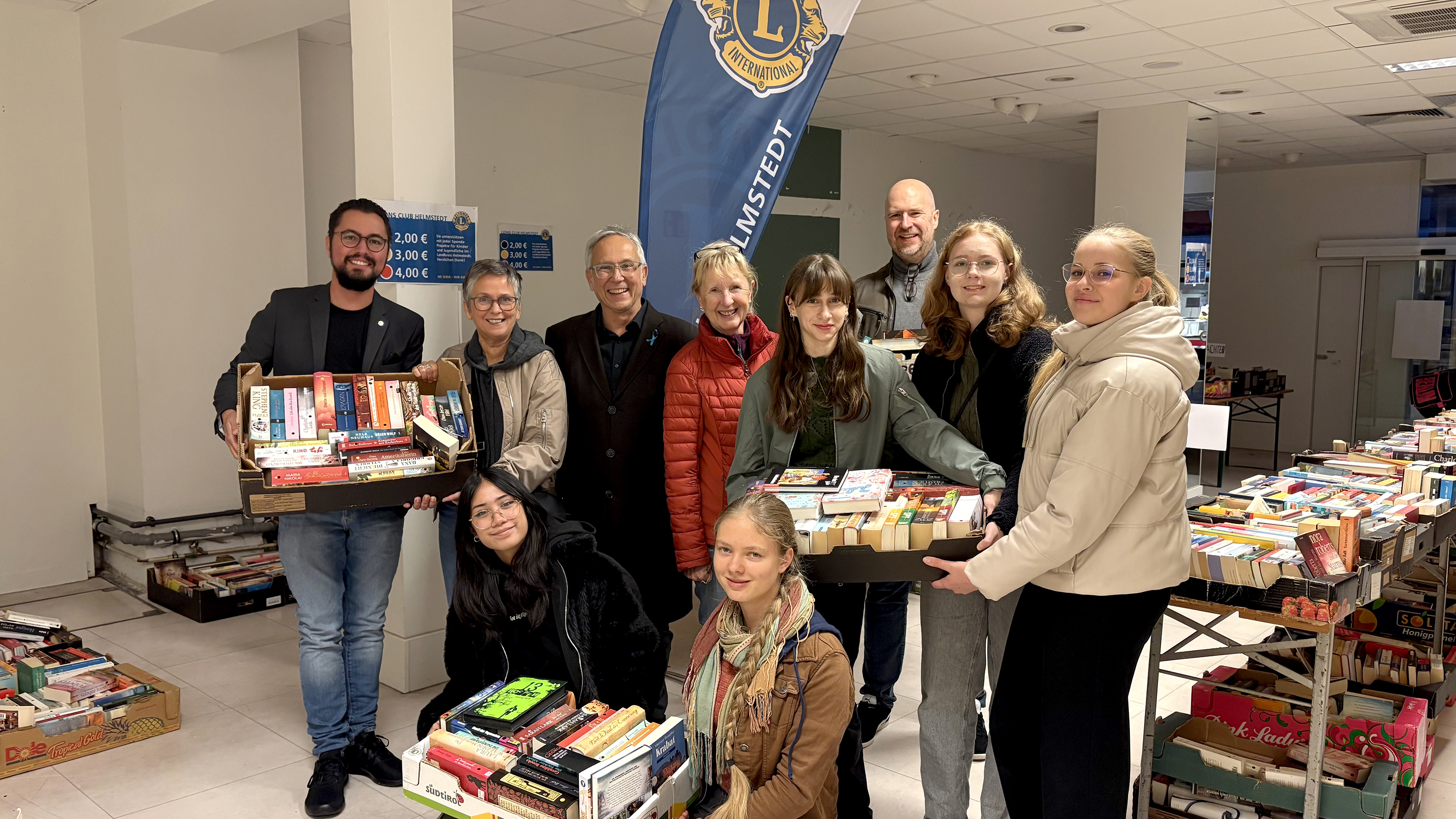 Lions-Präsident Andreas Warmbein, Lehrerin Juliane Hackmann, Lions-Vorstandsmitglied Dr. Joachim Scherrieble, Lions-Bücherverantwortliche Cordula Schwarz, Marta Zarichna, Julianum-Schulleiter Lars Herrmann, Hannah Linzel, Sophia Jawni (hinten v.l.), Aliana Kielgast und Jette Otto (vorne v.l.) bei der Übergabe im Rahmen des Bücherflohmarkts beim Helmstedter Gänsemarkt am 2. November 2025.
